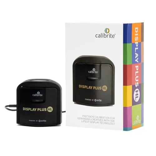 Calibrite Display Plus HL monitor calibration colorimeter on a desk next to a laptop